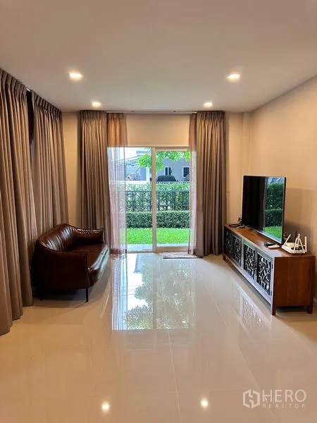 บ้าน ขายในPrawet, Bangkok - มุมนั่งเล่นหันสู่สวน มีโซฟา ทีวี และประตูกระจกเต็มบาน