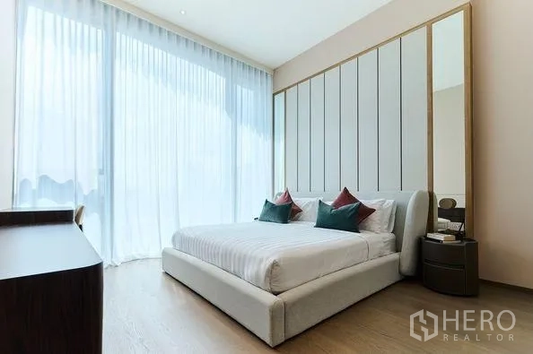 Condominium for rent in Pathum Wan, Bangkok - Serene bedroom with king-size bed, full-height windows and a paneled headboard.