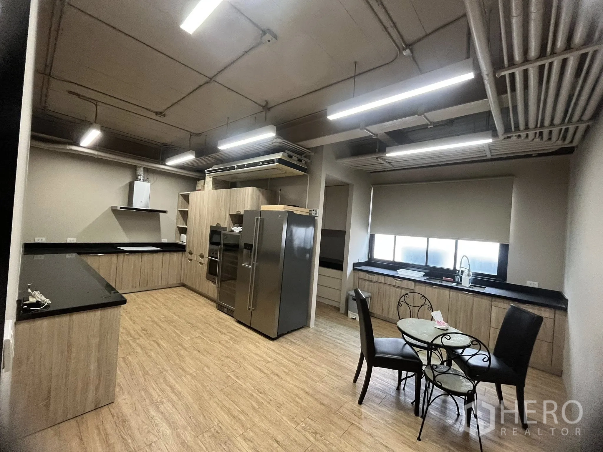 Home Office for rent in Watthana, Bangkok - Large fitted kitchen with wood cabinetry, black countertops, and a stainless refrigerator.