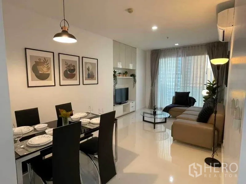 Condominium for rent or sale in Watthana, Bangkok - Open-plan living and dining room with sofa, TV unit and balcony doors.