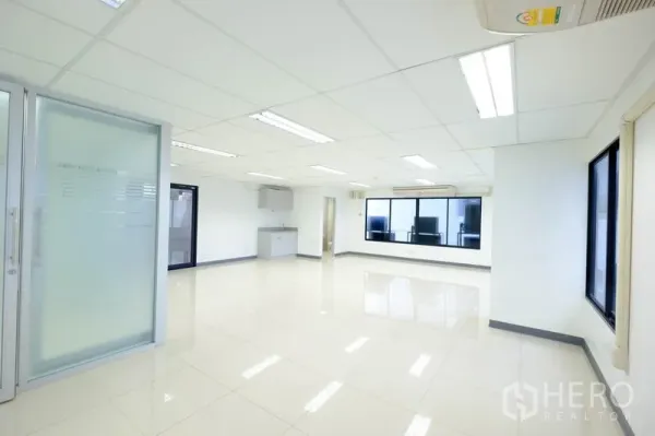 办公空间 出租在Chatuchak, Bangkok - 办公室一角，大窗户、磨砂玻璃推拉门、茶水间与空调。