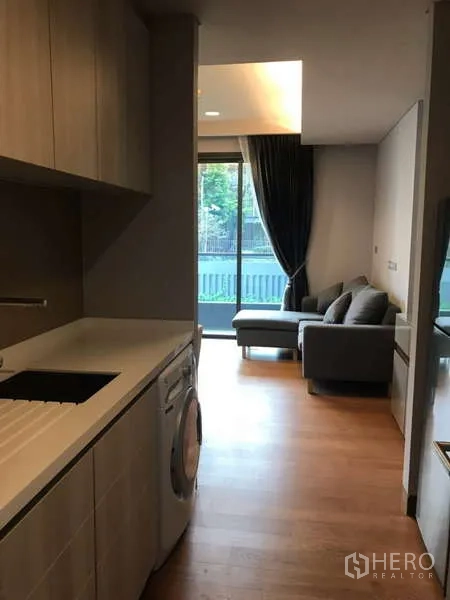 คอนโด ให้เช่าในKhlong Toei, Bangkok - ครัวแบบแกลเลย์พร้อมตู้บิวท์อินและเครื่องซักผ้า เชื่อมต่อสู่ห้องนั่งเล่นและระเบียง