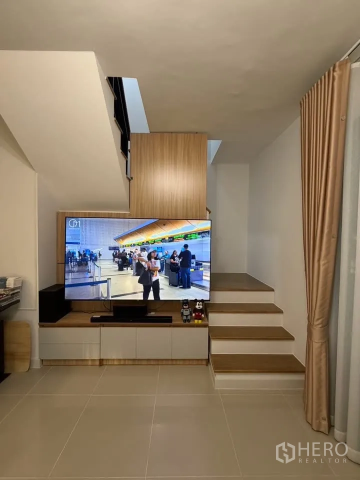 Townhouse for rent in Bang Phli, Samut Prakan - Close-up of built-in TV cabinet under the stairs with steps and curtain beside.