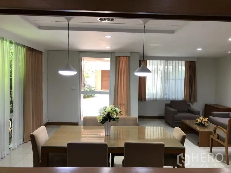 Detached House for rent in Watthana, Bangkok - Open-plan living and dining space with large windows, curtains and recessed lighting.