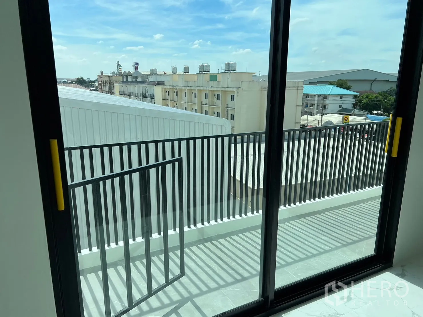 货栈 出租在Samut Prakan - 带金属栏杆的阳台与推拉门，眺望周边工业建筑。