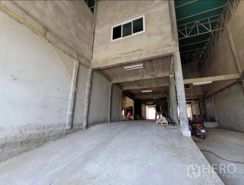 Warehouse for rent or sale in Sai Noi, Nonthaburi - Internal loading ramp leading to a raised platform and mezzanine under a steel truss roof.