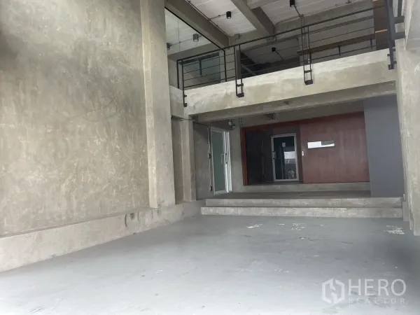 Home Office for rent in Suan Luang, Bangkok - Double-height concrete lobby with mezzanine level and industrial metal railings.