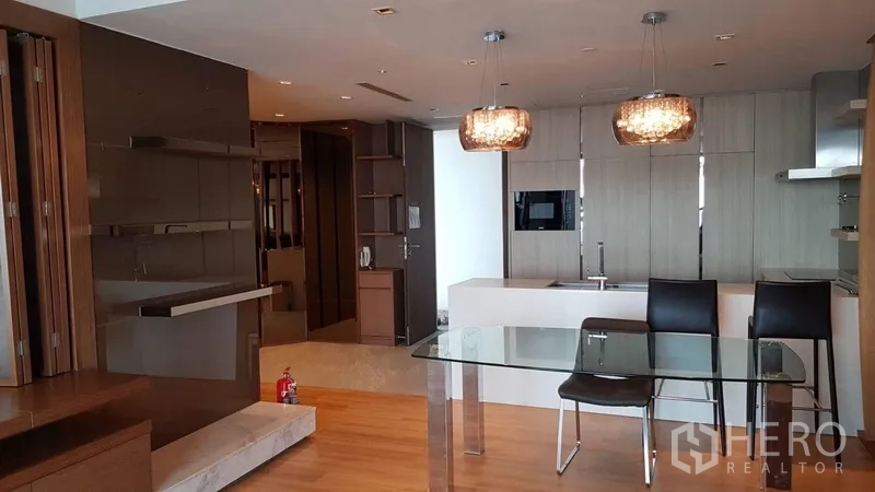 Condominium for rent in Yan Nawa, Bangkok - Dining space adjacent to a sleek kitchen island and pendant lights with built-in cabinetry.
