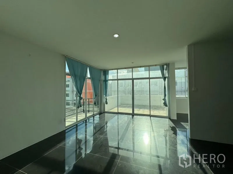 Warehouse for rent or sale in Chon Buri - Corner glass room with black tiles and sliding doors to an outdoor terrace.