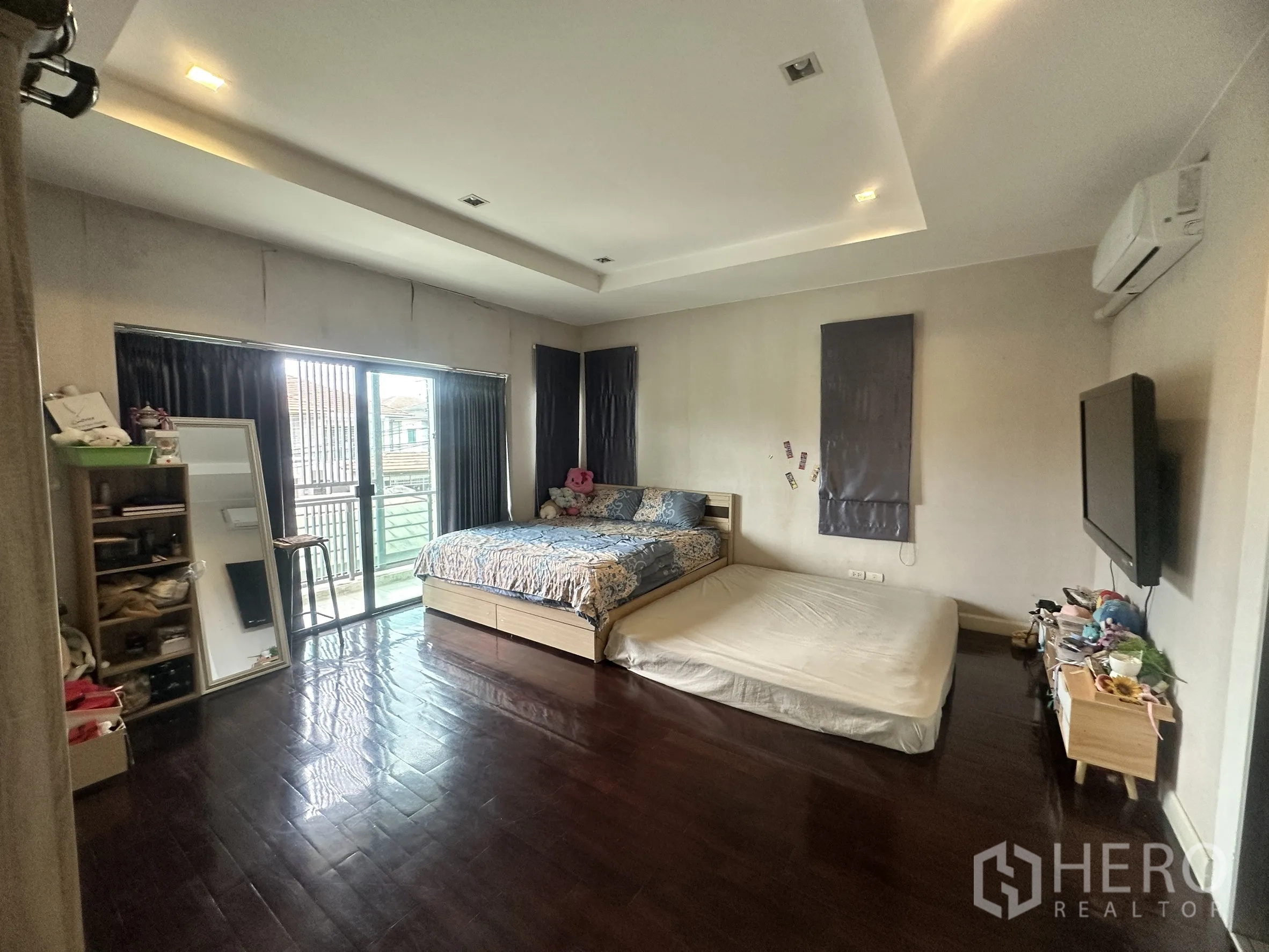Detached House for sale in Pak Kret, Nonthaburi - Large master bedroom with balcony access and wood flooring.