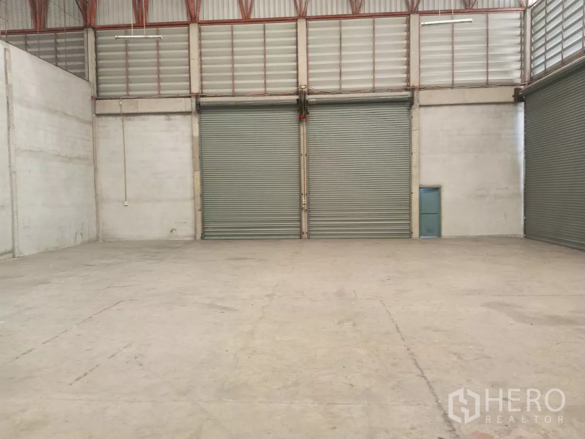Warehouse for rent in Min Buri, Bangkok - Column-free warehouse interior with high ceiling and two large roller shutter doors.