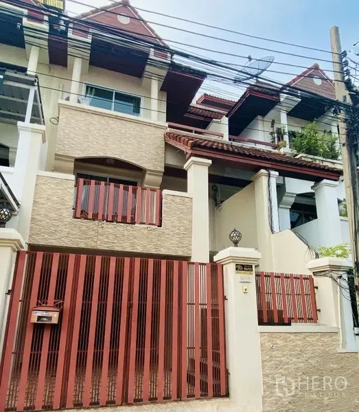 Townhouse for rent in Prawet, Bangkok - Three-storey Bangkok townhouse exterior with red metal gate and balconies.