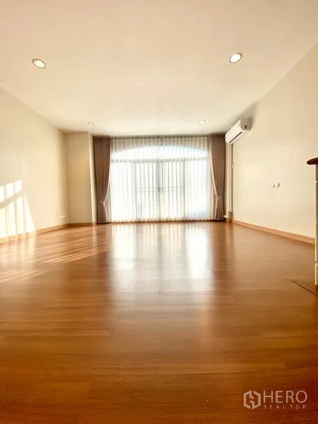 联排别墅 出租在Prawet, Bangkok - 楼上大房间，木地板、空调与通往阳台的纱帘大窗。