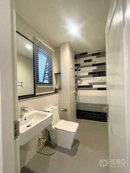 บ้าน ขายในBang Kruai, Nonthaburi - ห้องน้ำพร้อมโซนอาบน้ำแบบ Walk‑in ผนังลายกระเบื้องขาวดำ โถสุขภัณฑ์และอ่างล้างหน้า
