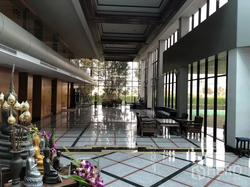 工厂 出租在Bang Bua Thong, Nonthaburi - 挑高前厅，整面玻璃、接待座位与光亮地面，面向绿化