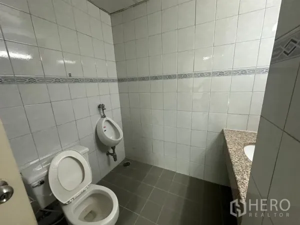办公空间 出租在Watthana, Bangkok - 办公室卫生间，瓷砖墙地，配坐便器、尿斗与花岗岩台面洗手盆。