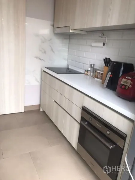 คอนโด ขายในKhlong Toei, Bangkok - ครัวตัวแอลตู้สีขาว เตาไฟฟ้า และเตาอบบิลต์อิน