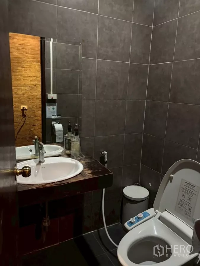 店屋 出租在Watthana, Bangkok - 深色瓷砖卫生间，盥洗台与喷枪马桶。