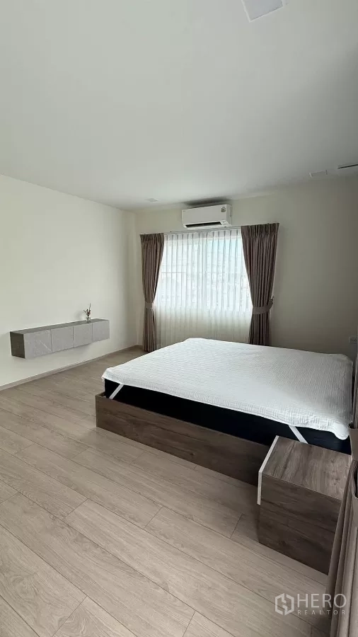 บ้าน ให้เช่าในBang Phli, Samut Prakan - ห้องนอนหลักเตียงคู่ พื้นไม้ และผ้าม่านหน้าต่าง.