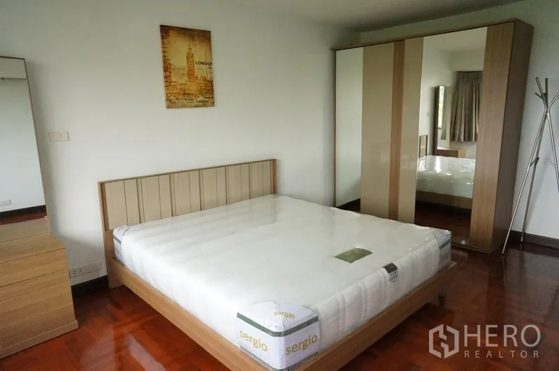 Condominium for rent in Watthana, Bangkok - Bright bedroom with queen bed, mirrored wardrobe and bedside dresser.