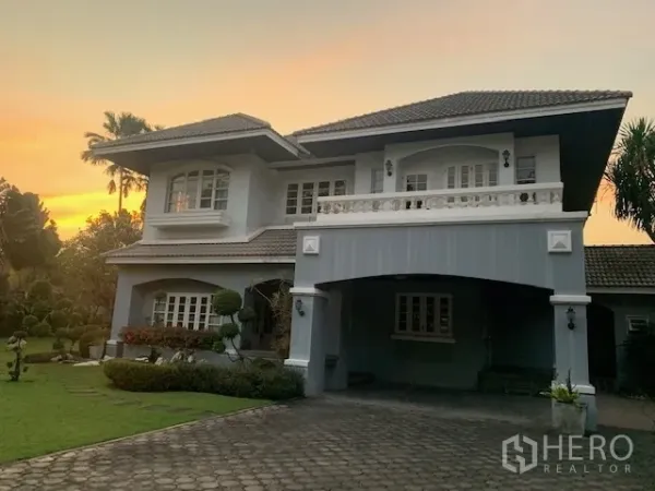 独立式住宅 出租在Khan Na Yao, Bangkok - 两层独栋别墅外观，带有顶棚车位、阳台与大前院，黄昏时分。