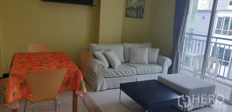 คอนโด ให้เช่าในKhlong Toei, Bangkok - ห้องนั่งเล่นโซฟาลายทาง ชุดโต๊ะทานข้าว โต๊ะกลาง และประตูสไลด์ออกระเบียง