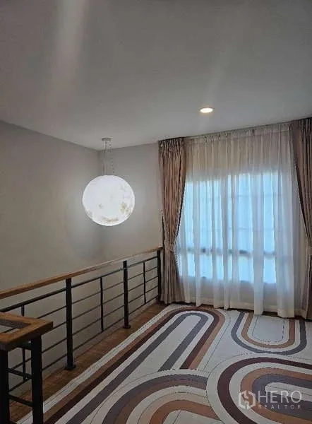 Detached House for rent in Bang Phli, Samut Prakan - Upstairs landing with metal handrail, patterned rug and floor-to-ceiling window.
