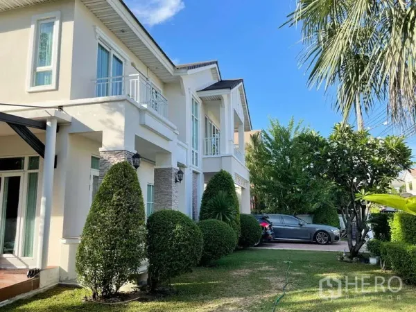 独立式住宅 出租在Prawet, Bangkok - 房屋侧立面与阳台，搭配景观花园与成树。