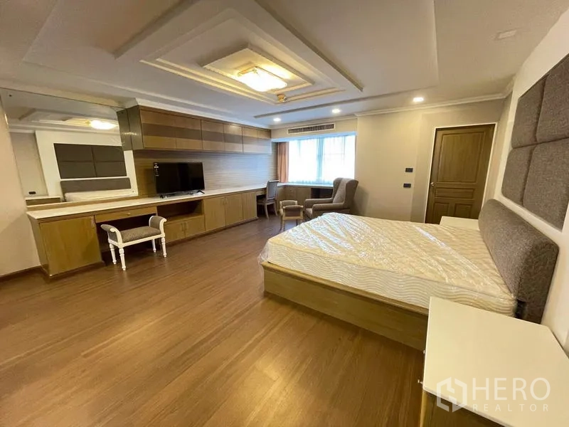 Condominium for rent in Watthana, Bangkok - Large bedroom with extensive built-in cabinetry, accent headboard, and recessed lighting.