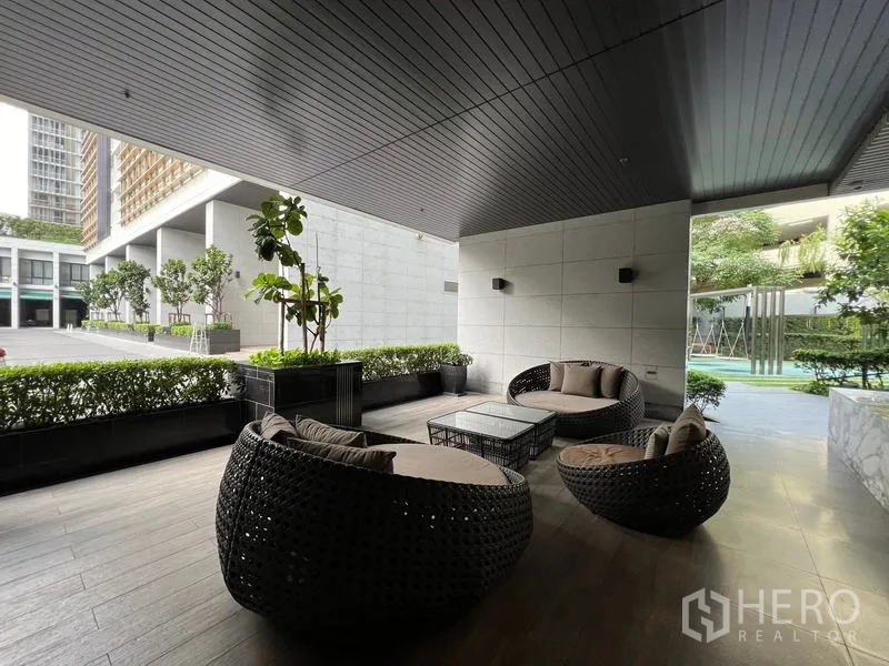 คอนโด ขาย - พื้นที่นั่งเล่นกลางแจ้งใต้หลังคา ชุดโซฟาหวายใกล้สระและสวน