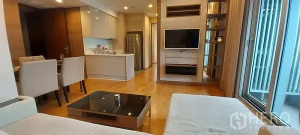 Condominium for rent in Ratchathewi, Bangkok - Open-plan living room with sofa, wall-mounted TV, and modern kitchenette.