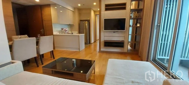 Condominium for rent in Ratchathewi, Bangkok - Open-plan living room with sofa, wall-mounted TV, and modern kitchenette.
