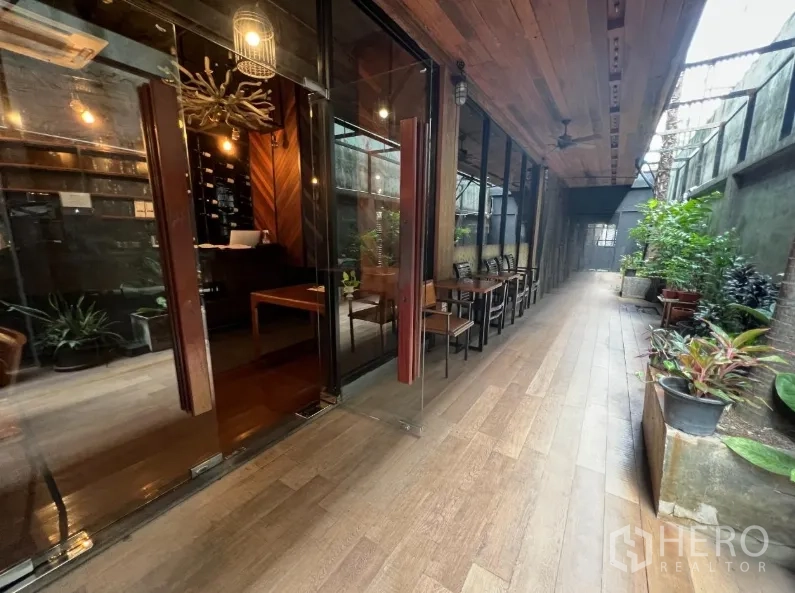 พื้นที่ขายปลีก ให้เช่าในWatthana, Bangkok - ทางเดินระเบียงมีหลังคา หน้าร้านกระจก พันธุ์ไม้กระถาง และพื้นลายไม้