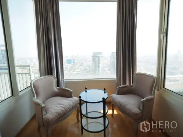 Condominium for rent in Sathon, Bangkok - Window nook with two armchairs and a round glass table overlooking the Bangkok skyline.