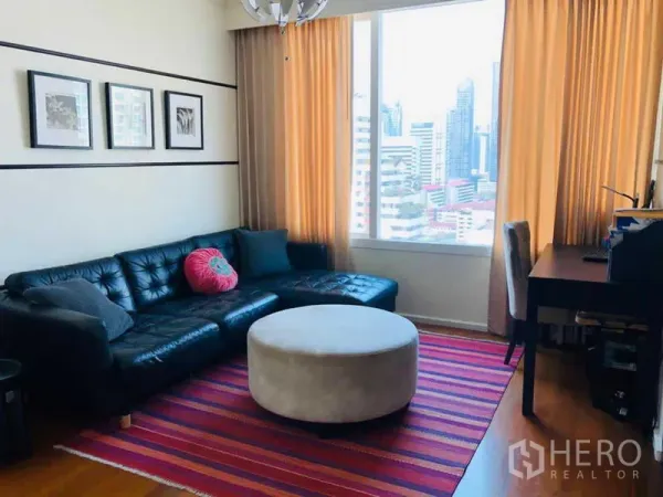 คอนโด ให้เช่าในWatthana, Bangkok - ห้องนั่งเล่น โซฟาหนังสีดำ โต๊ะทำงาน และหน้าต่างบานใหญ่ชมวิวเมือง.