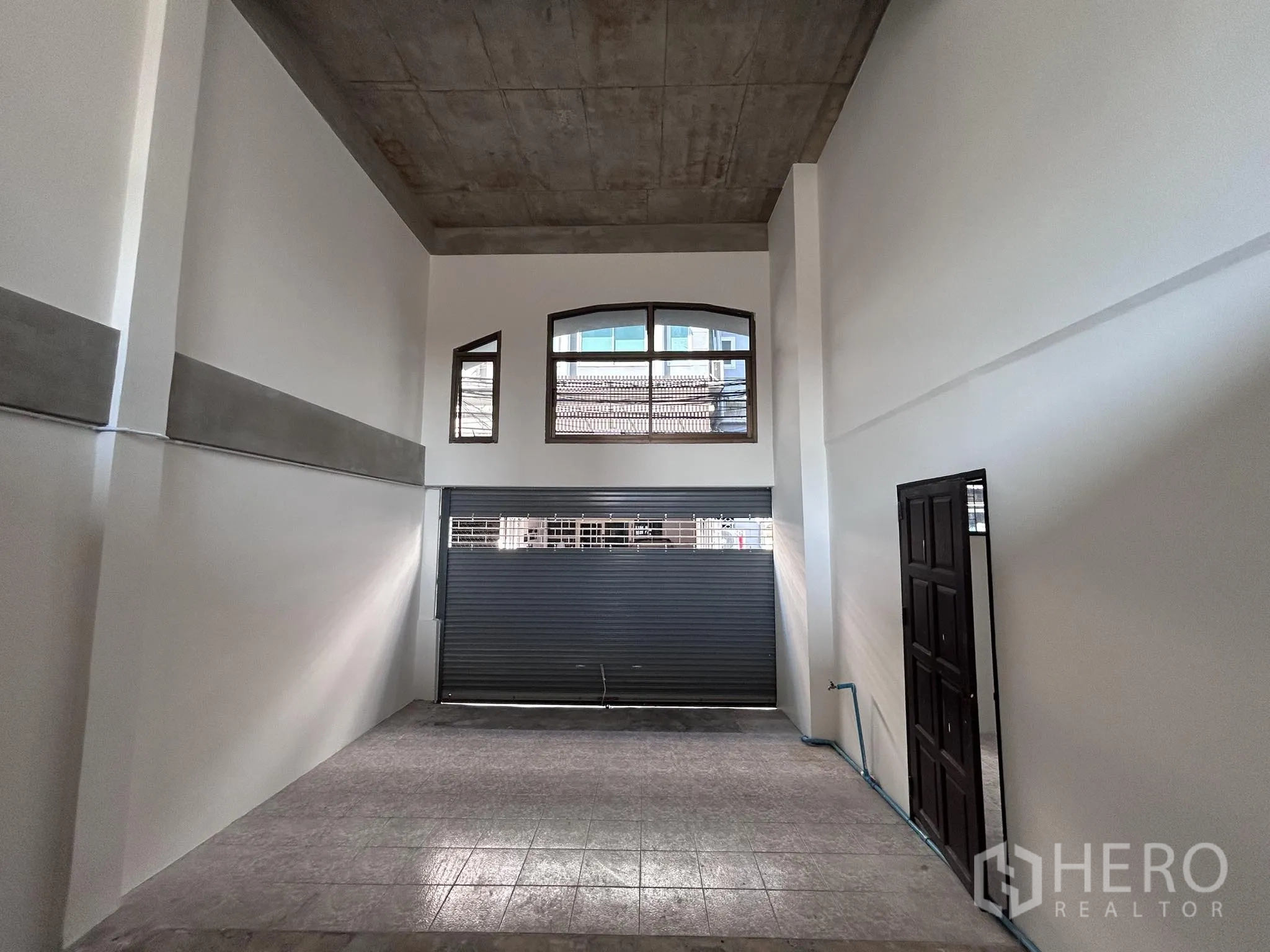 家庭办公室 for rent or sale in Watthana, Bangkok - 首层开放空间，挑高天花并配金属卷帘门。