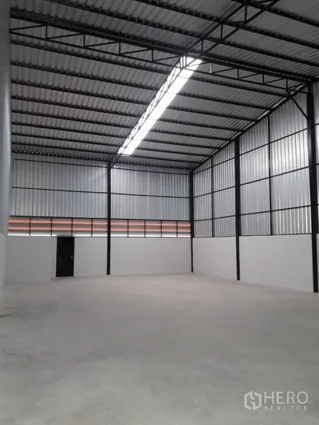 货栈 出租在Lam Luk Ka, Pathum Thani - 仓库内部，约7米挑高钢结构屋顶，中部天窗灯带与混凝土地面。