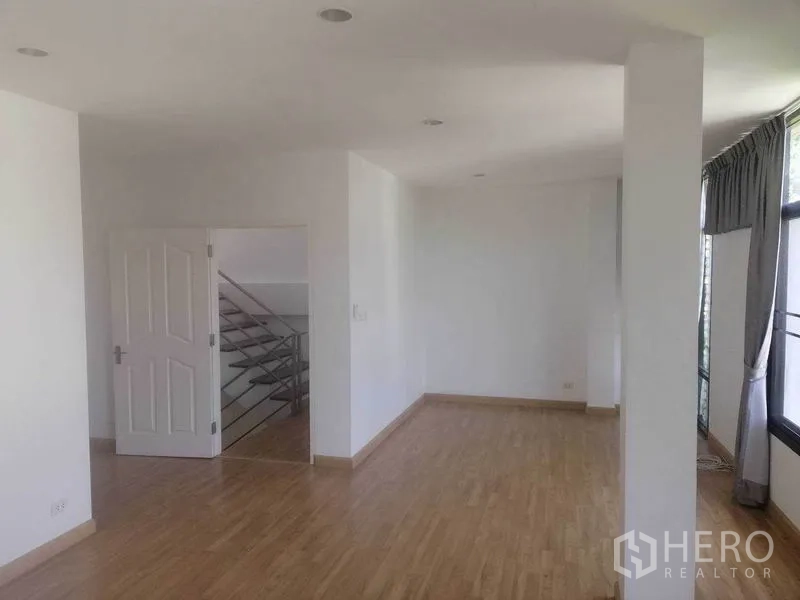 Townhouse for rent in Wang Thonglang, Bangkok - Open-plan living area with wood flooring, recessed lights and a view of the staircase.