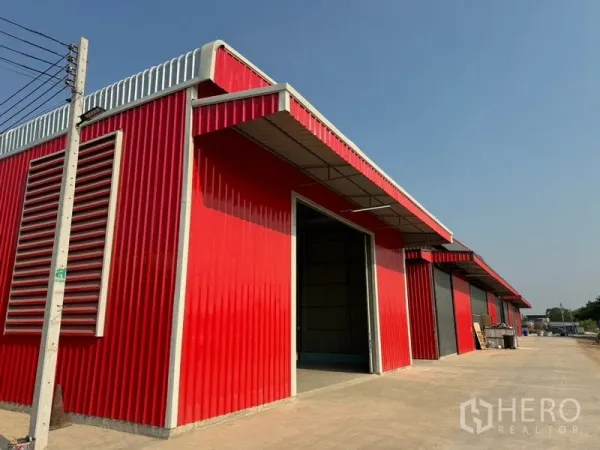 货栈 出租在Lam Luk Ka, Pathum Thani - 红灰相间的多间仓库排屋，侧墙通风百叶，沿道路排列。