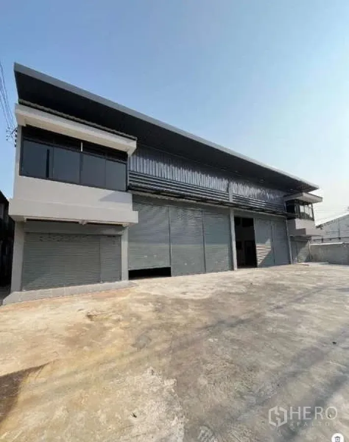 Warehouse for rent in Phra Samut Chedi, Samut Prakan - Angled perspective of a long warehouse block with corner offices, canopy cover, and ample parking and turning space.