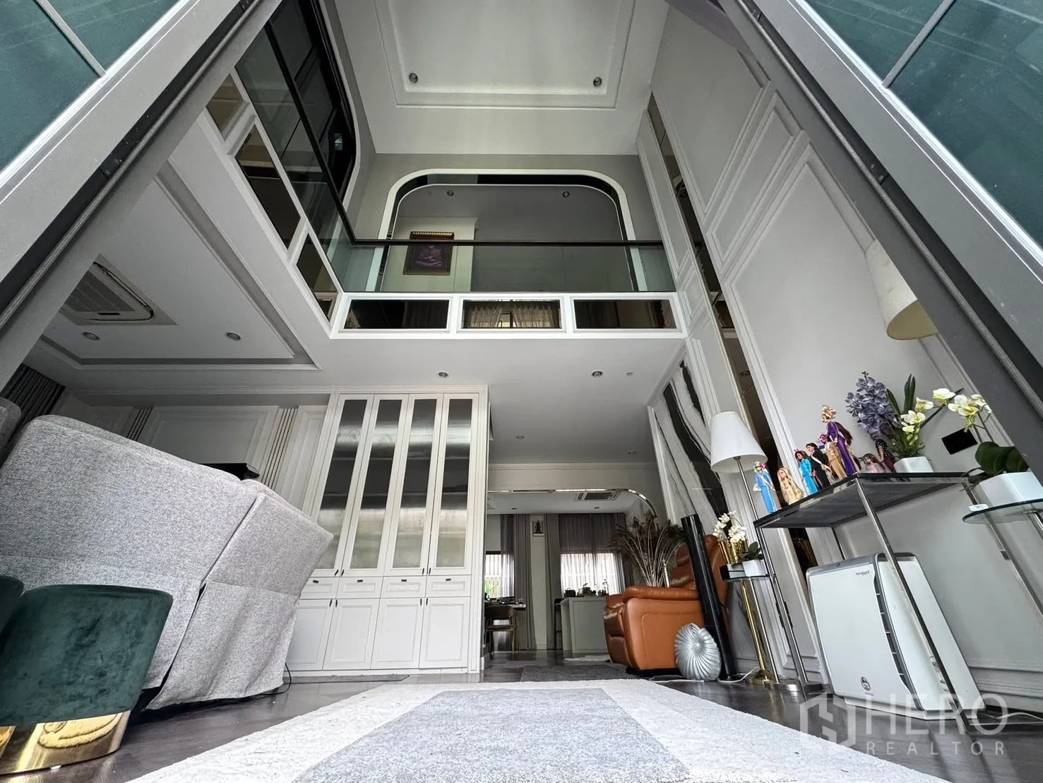 独立式住宅 出售在Mueang Pathum Thani, Pathum Thani - 挑高客厅，夹层玻璃栏杆与定制柜体。