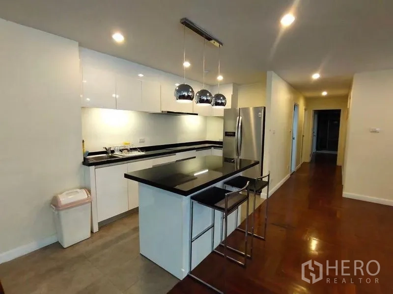 Condominium for rent or sale in Bang Rak, Bangkok - Sleek kitchen with black stone island, pendant lights, and stainless‑steel fridge.