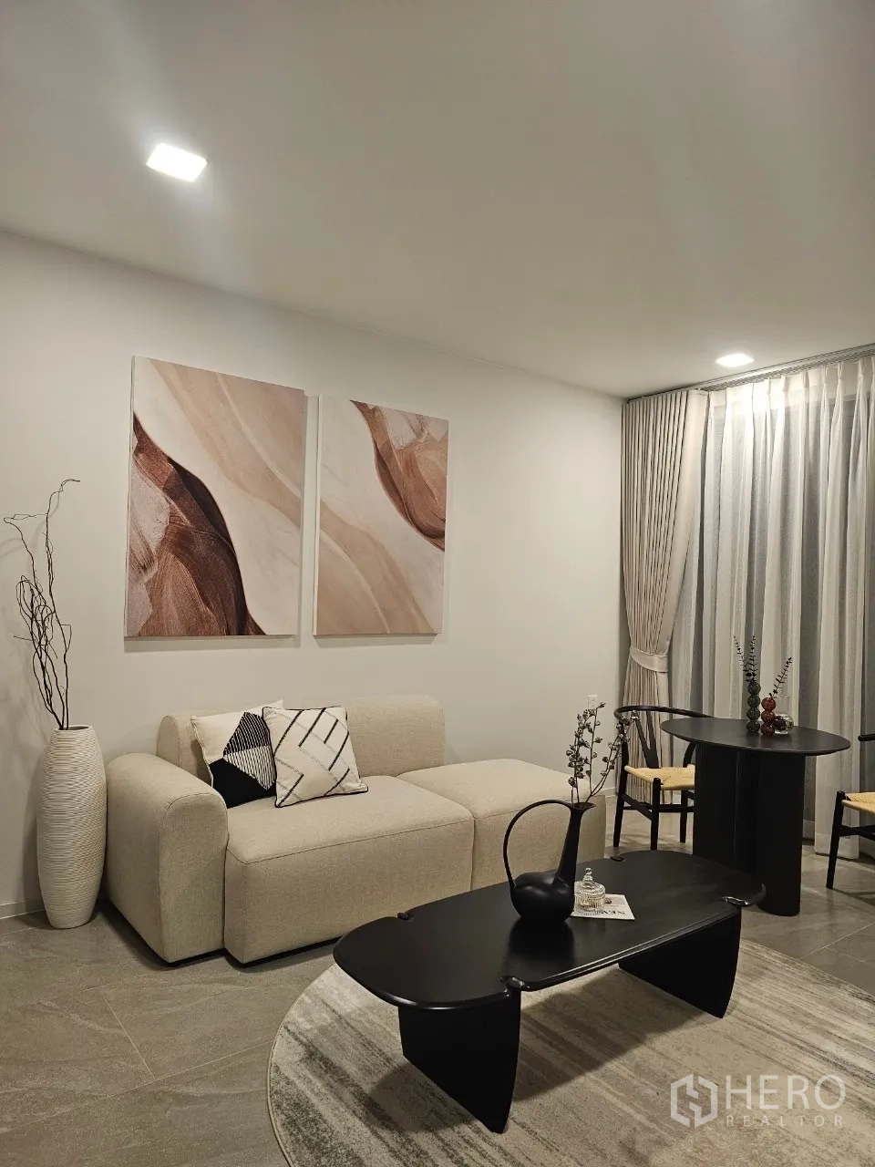 独立式住宅 出租在Saphan Sung, Bangkok - 温馨小客厅，米色沙发、黑色茶几与窗帘。