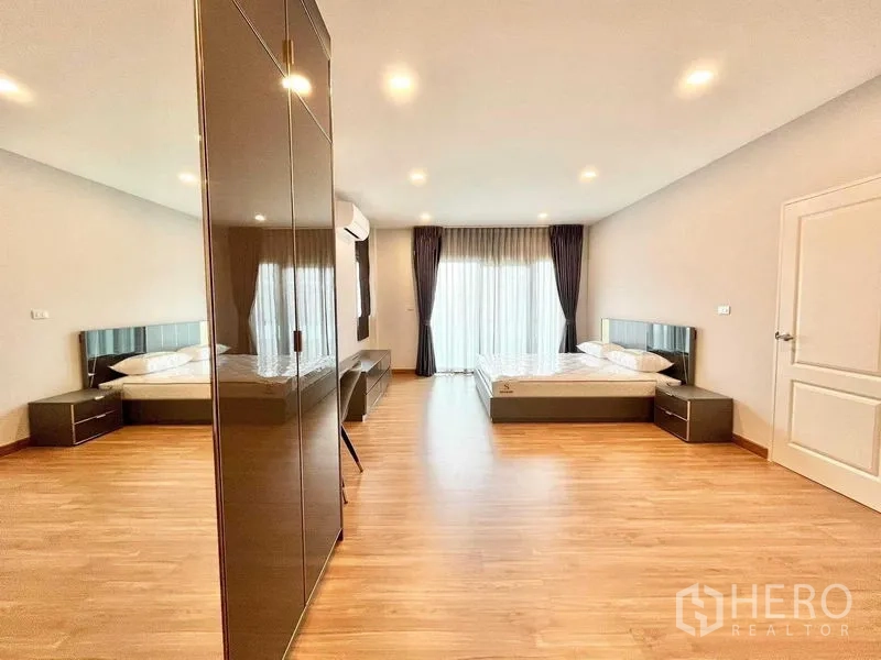 Detached House for rent in Don Mueang, Bangkok - Large master bedroom with wood floors, balcony doors and twin beds.
