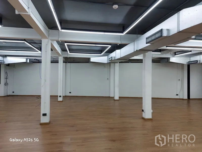 สำนักงานที่บ้าน ให้เช่าในKhlong Toei, Bangkok - โถงสำนักงานโล่ง พื้นไม้ เสารับน้ำหนักสีขาว และไฟ LED ตีกรอบสี่เหลี่ยม