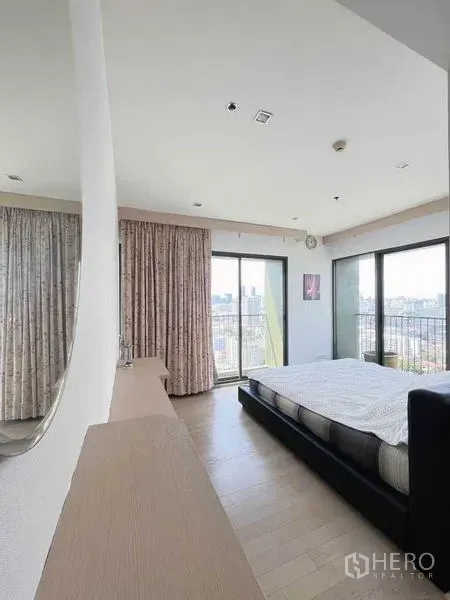 Condominium for sale - Corner bedroom with wraparound windows, balcony access, and city views in Noble Solo Thonglor.
