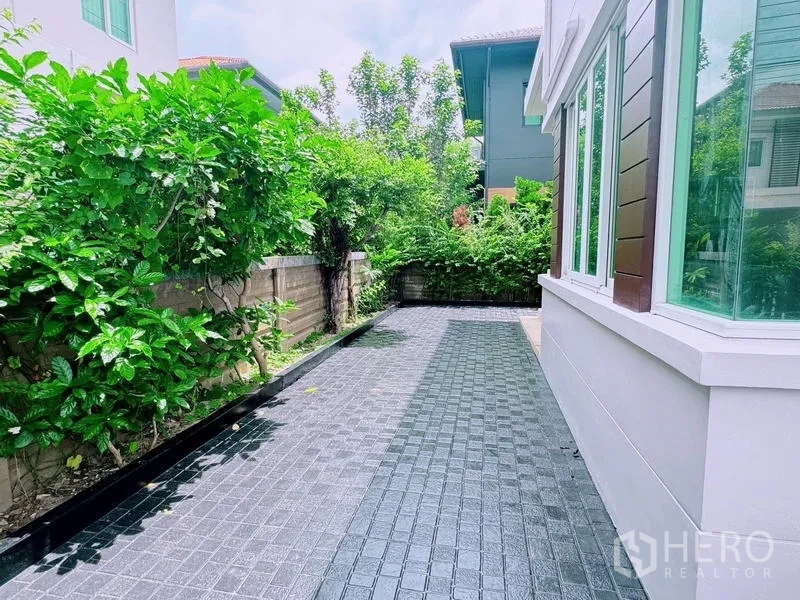 Detached House for rent in Prawet, Bangkok - Side garden walkway paved and lined with lush greenery.