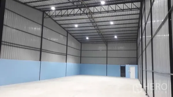 คลังสินค้า ให้เช่าในPak Kret, Nonthaburi - พื้นที่โกดังแบบโอเพ่นแพลน ผนังทาสีฟ้า ประตูบานเลื่อนขนาดใหญ่ พร้อมประตูทางคนเข้าออก