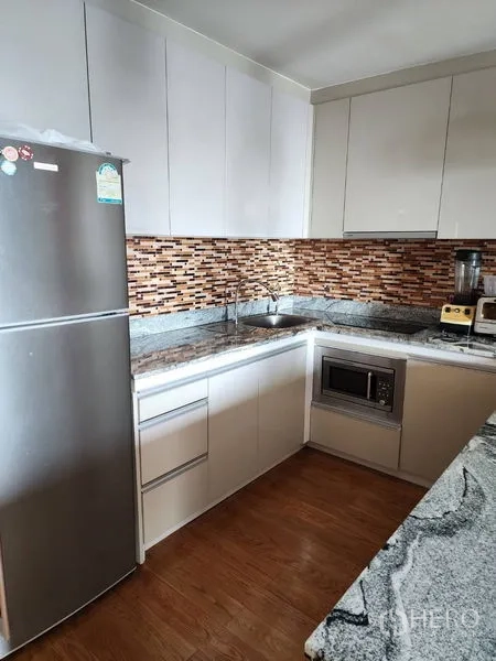 公寓 出租在Bang Rak, Bangkok - 现代L型厨房，花岗岩台面、马赛克挡水板、不锈钢冰箱与嵌入式微波炉。