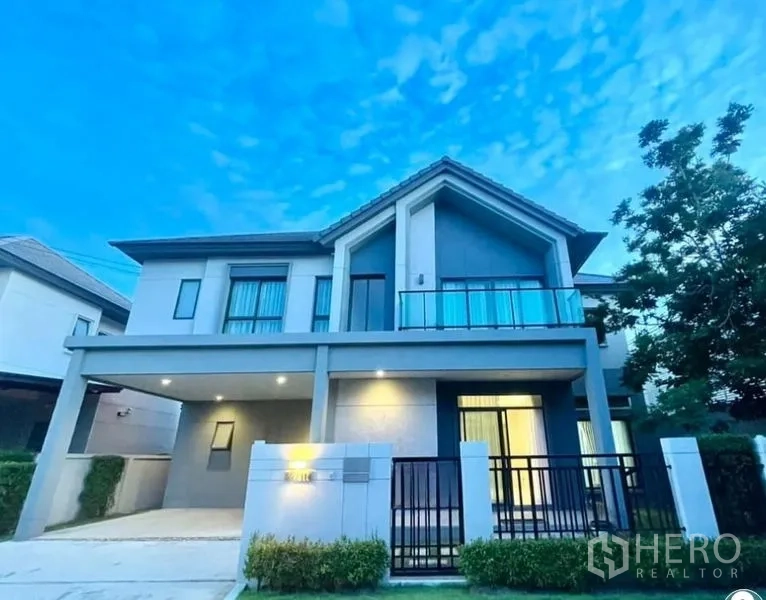 บ้าน ขายในBang Kruai, Nonthaburi - บ้านเดี่ยวสองชั้นสไตล์โมเดิร์น มีกำแพงรั้ว ประตูหน้าบ้าน ที่จอดรถมีหลังคา และระเบียงกระจกยามโพล้เพล้